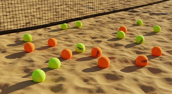 Várias bolas de beach tennis coloridas espalhadas na areia